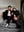 A portrait of two individuals sitting on stairs, with one leaning on the other. The individuals appear to be posing in a studio-like environment. blurred out low res